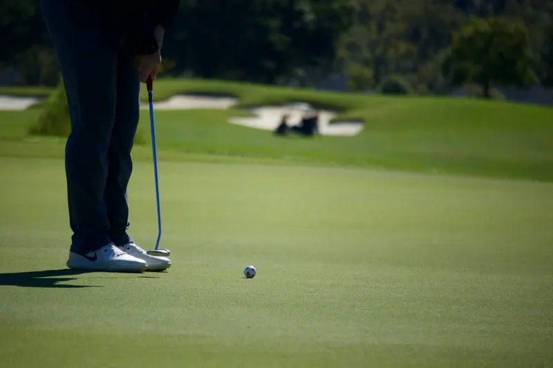 Unrecognizable golfer puts on a lush green course under clear skies