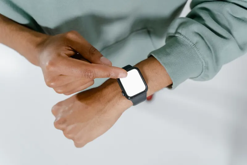 Close-up of a person in a green sweater using a smartwatch