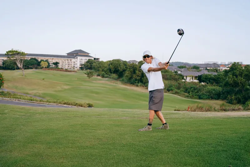 A golfer swings his club on a lush green course, capturing the essence of the sport