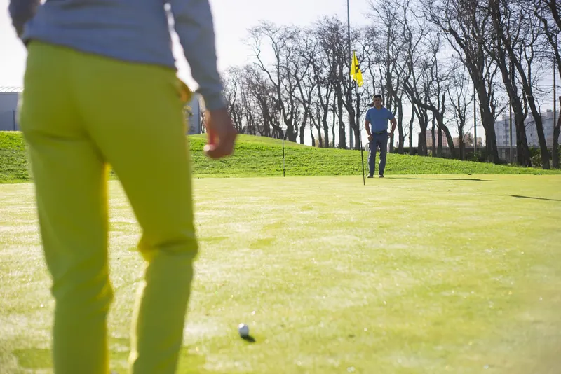 Two golfers playing on a lush green course with clear sky in Portugal